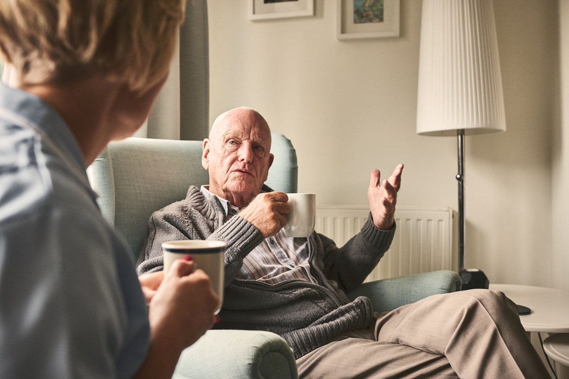 Elderly man having conversation with female carer